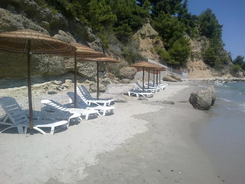a group of chairs and umbrellas on a beach at Thea Hotel in Possidi