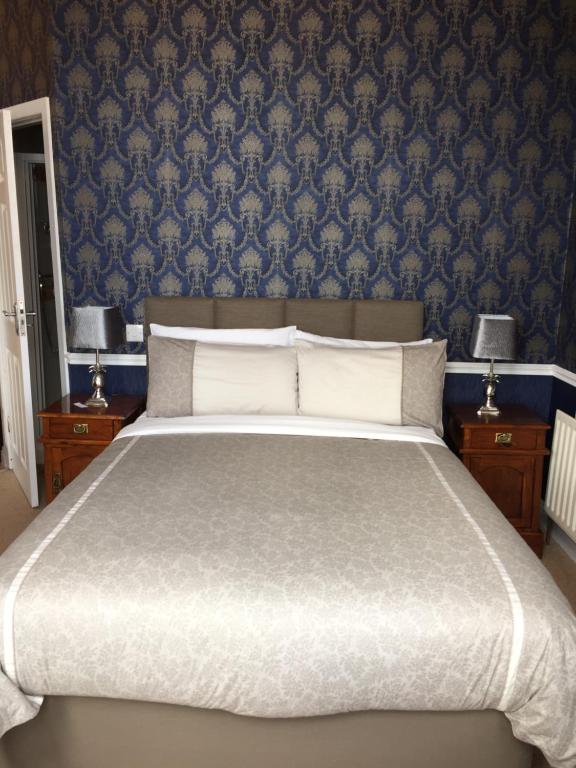 a bedroom with a large bed with blue wallpaper at Albany Lodge in Portrush