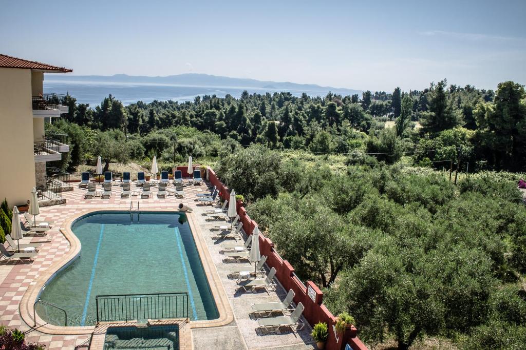 una piscina in un resort con sedie e alberi di Hotel Ilios a Kriopigi