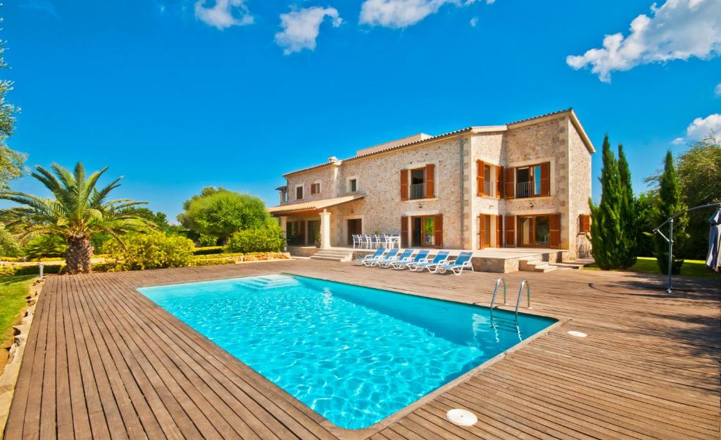 a villa with a swimming pool in front of a house at Finca Victoria in Alcudia