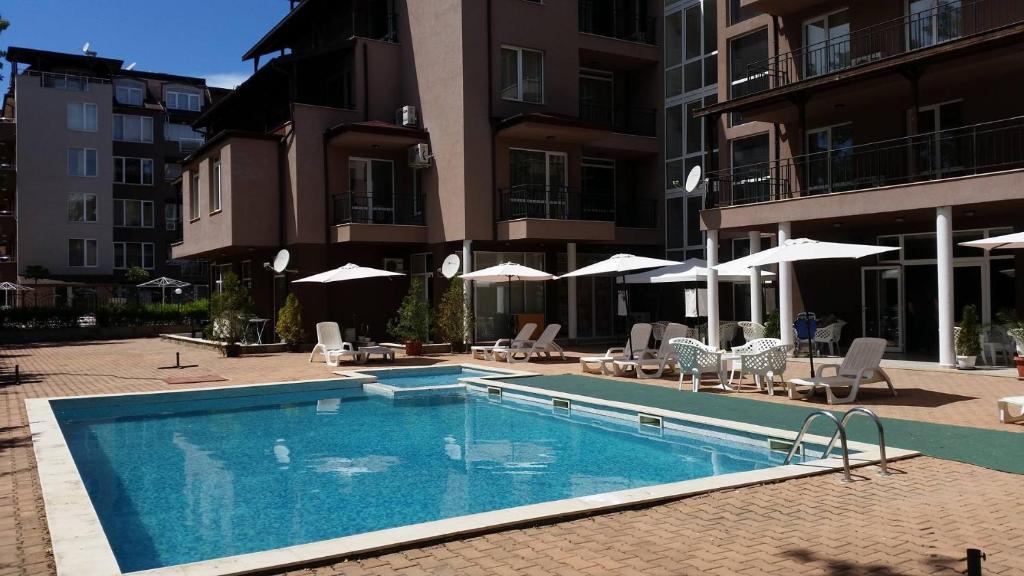 a swimming pool with chairs and umbrellas in front of a building at St. Sofia Apartments - Official Rental in Sunny Beach