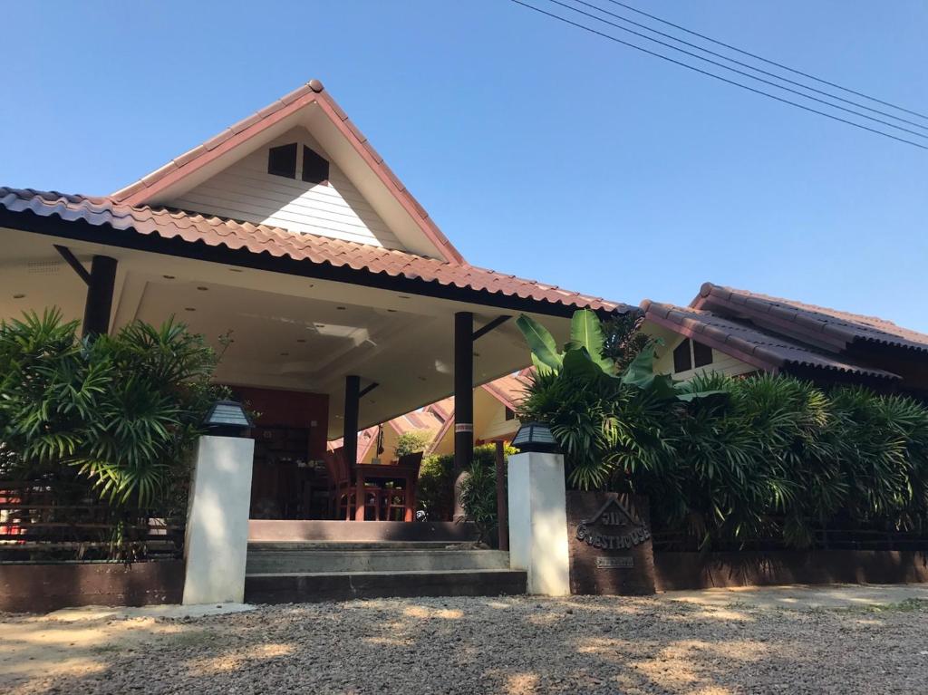 a house with a porch and some palm trees at Jim Guesthouse in Kanchanaburi