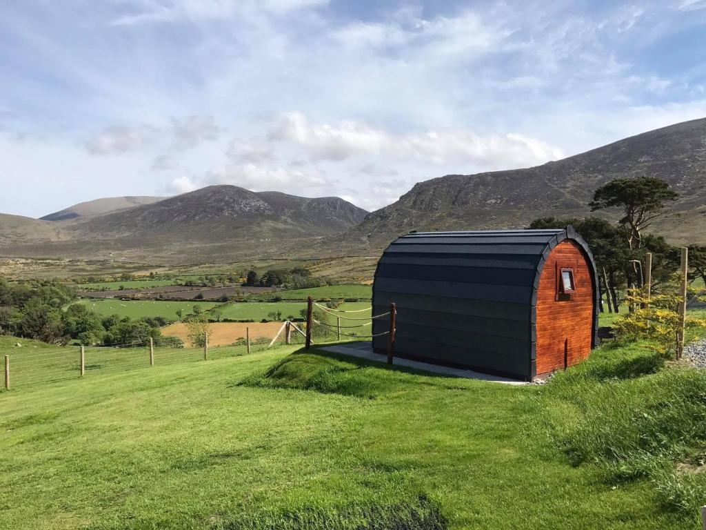 a shed in a field with mountains in the background at Gorse Hill Glamping in Newcastle