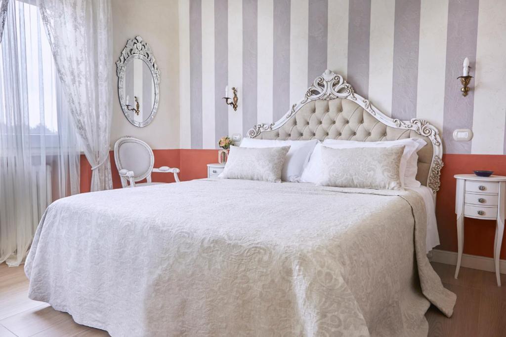 um quarto com uma cama grande e uma colcha branca em La Zarabba Boutique Hotel em Ponti Sul Mincio