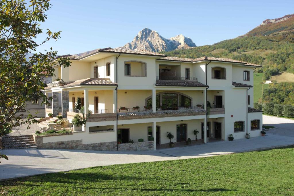 a large white house with a mountain in the background at Locanda Del Parco Hotel in Colledara