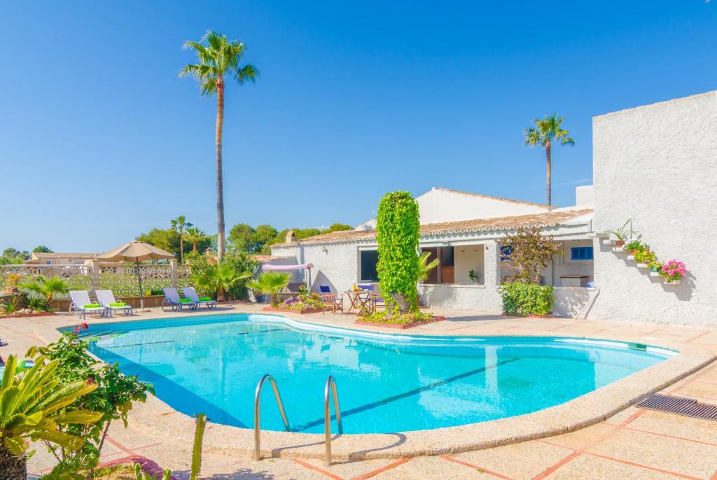 una piscina frente a una casa con palmeras en Torre Marina en Sa Ràpita