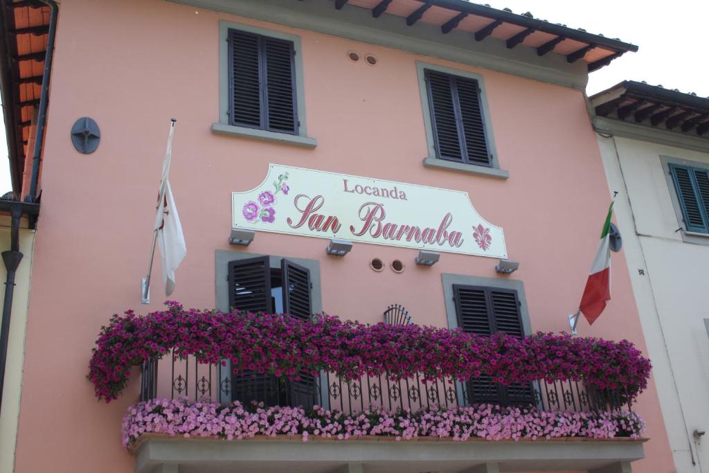 un bâtiment rose avec des fleurs sur un balcon dans l'établissement Locanda San Barnaba, à Scarperia