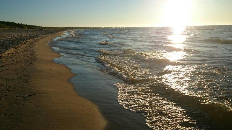 a beach with the sun reflecting on the water at Owk Korona in Mikoszewo