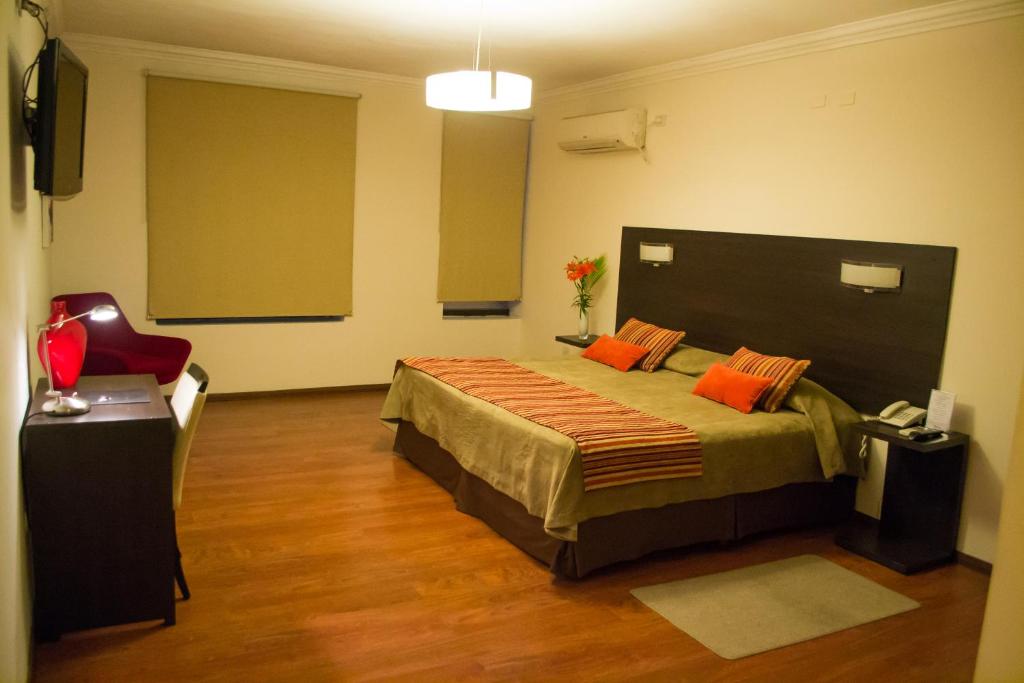 1 dormitorio con 1 cama grande con almohadas de color naranja en Hotel Las Vegas en Salta