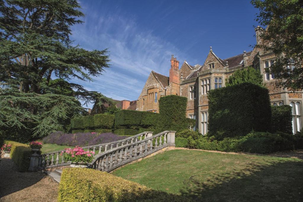 a large castle with a staircase in front of a yard at Fawsley Hall Hotel in Daventry