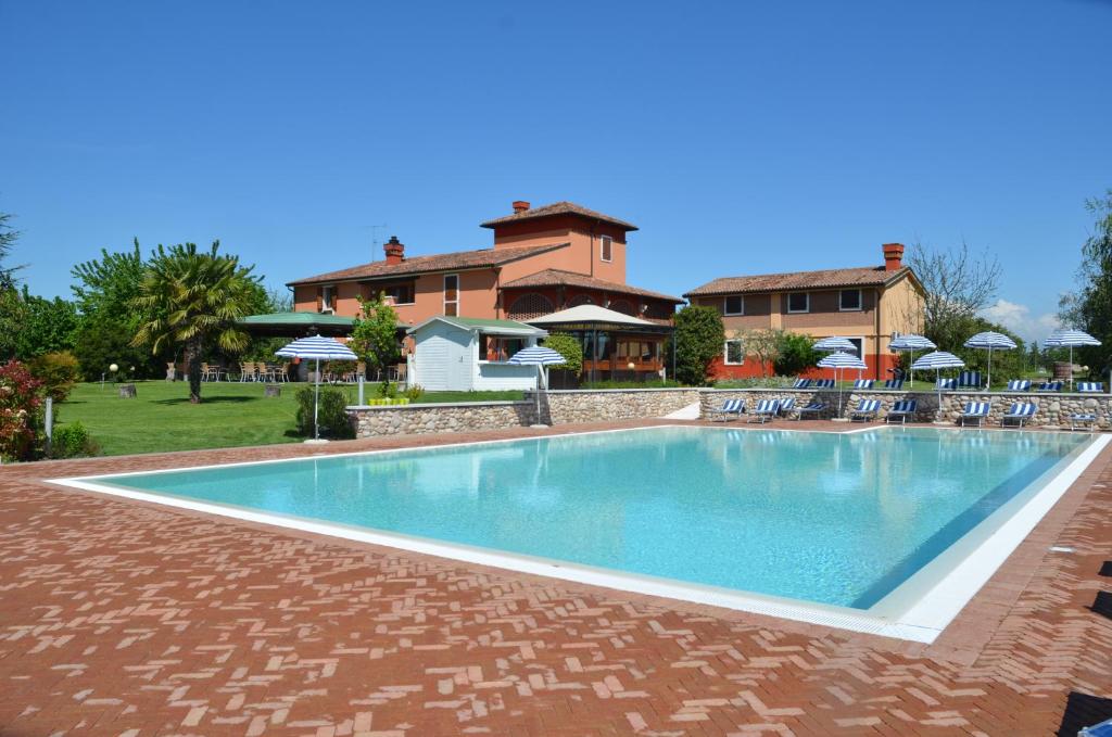 ein Pool mit Stühlen und ein Haus im Hintergrund in der Unterkunft Locanda Bella Italia in Castelnuovo del Garda