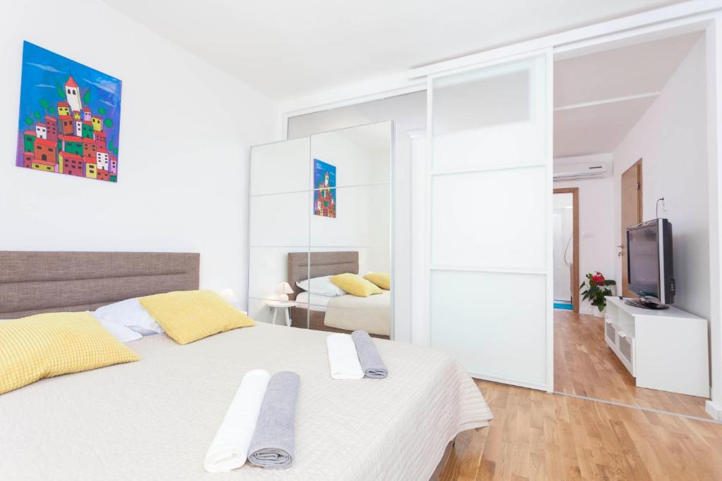 a white bedroom with a large white bed and a tv at Apartment Mikula in Makarska