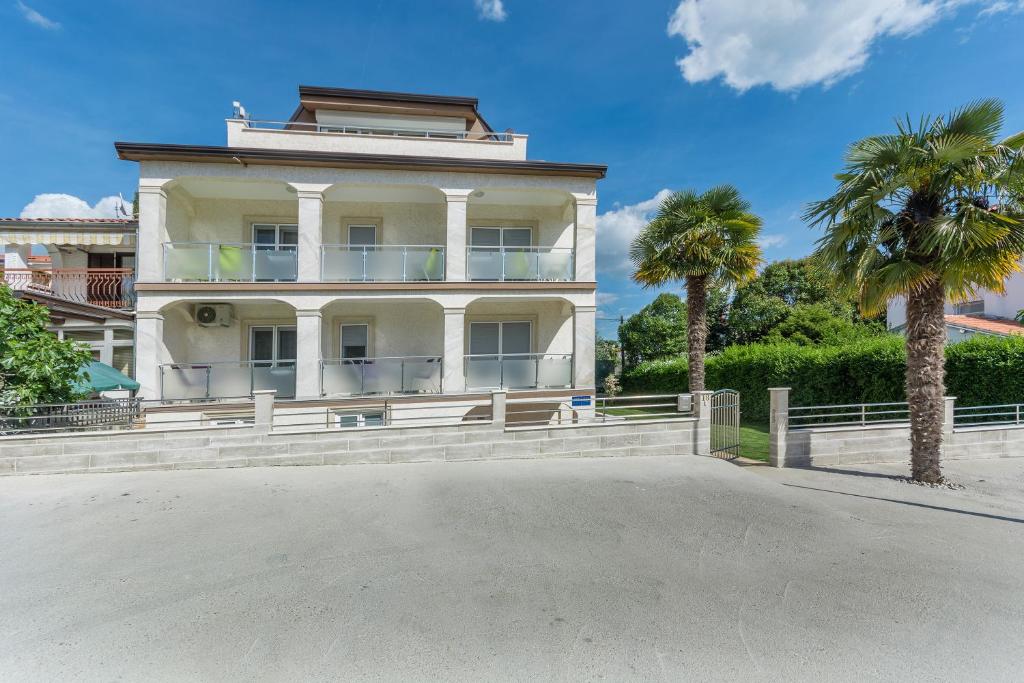 a large white house with palm trees in front of it at Villa Stephany in Poreč