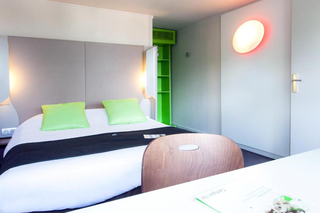 a hotel room with a bed with green pillows at Campanile Saint-Malo ~ Saint-Jouan-Des-Guerets in Saint-Jouan-des-Guérets