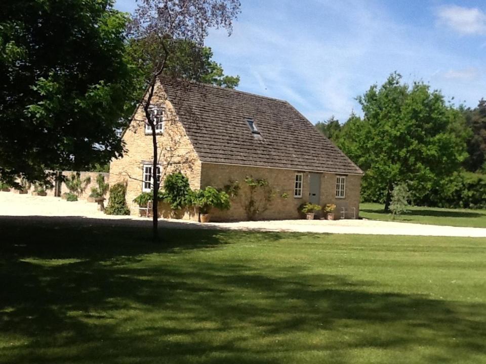 a large brick building with a large grass yard at Gardeners Cottage in Crudwell