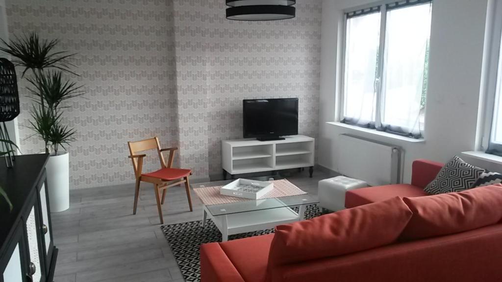 ein Wohnzimmer mit einem roten Sofa und einem TV in der Unterkunft Pause Messines Chez Thérèse in Verlinghem