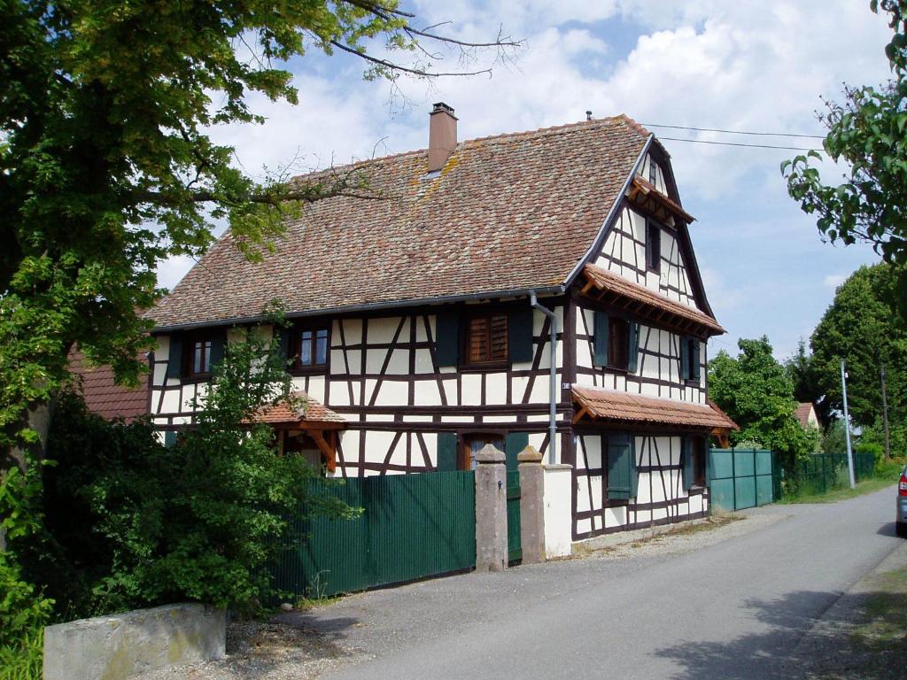 una casa blanca y negra con una valla verde en Gîte Nicole, en Heidolsheim