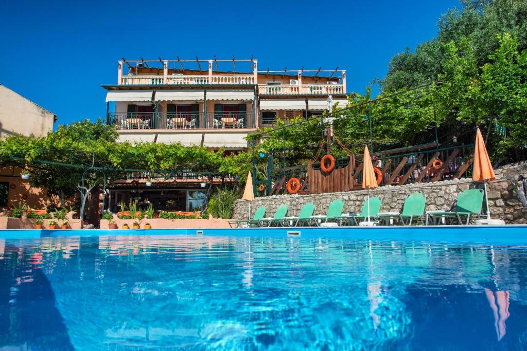 a swimming pool with chairs and a building in the background at Argo Poolside in Benitses