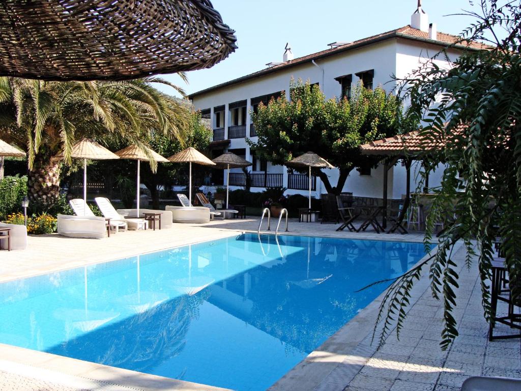 a swimming pool with chairs and umbrellas next to a building at Villa Rhapsody Pension in Kayakoy