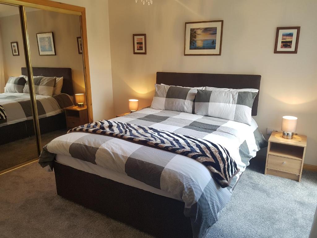 1 dormitorio con 1 cama grande y espejo en Ivy Cottage en Montrose