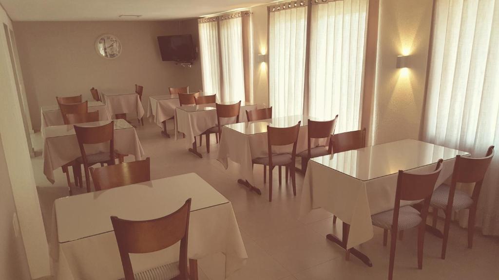 a dining room with white tables and chairs at Hotel Recanto in Lajeado
