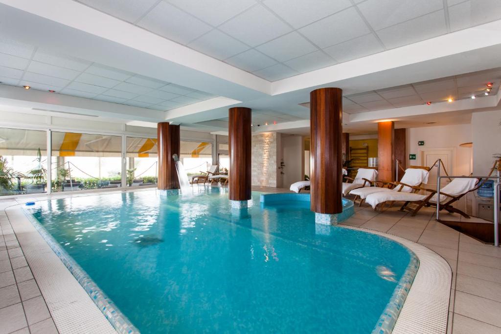 a large swimming pool in a hotel room with a hotel room at Hotel Villa Sorriso in Lido di Jesolo
