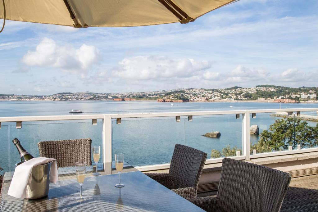 a table with wine glasses on a balcony with a view of the water at The Imperial Torquay in Torquay