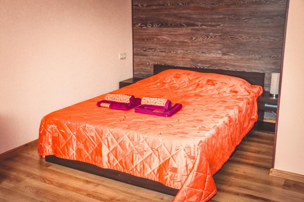 a bed with an orange comforter and two purple objects at Viktoria Apartment in Narva