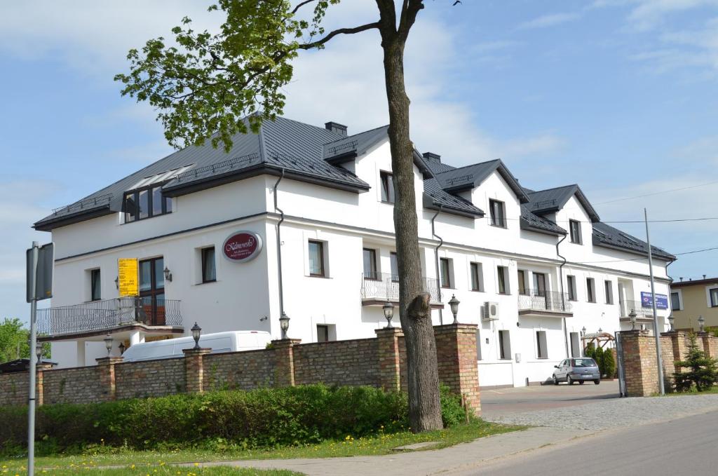 a white building with a black roof at Sala Bankietowa i Pokoje Gościnne in Sokółka