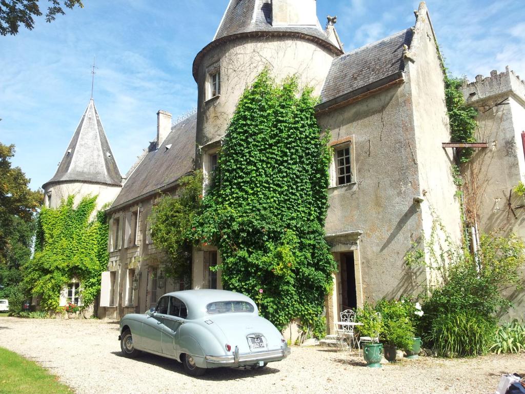 um carro velho estacionado em frente a um edifício em La chambre de la Tour em Lugon et l’Ile du Carney