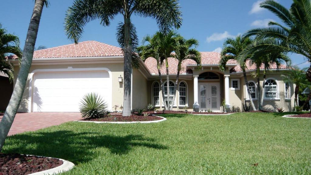 a house with palm trees in front of it at Villa Cape Florida in Cape Coral