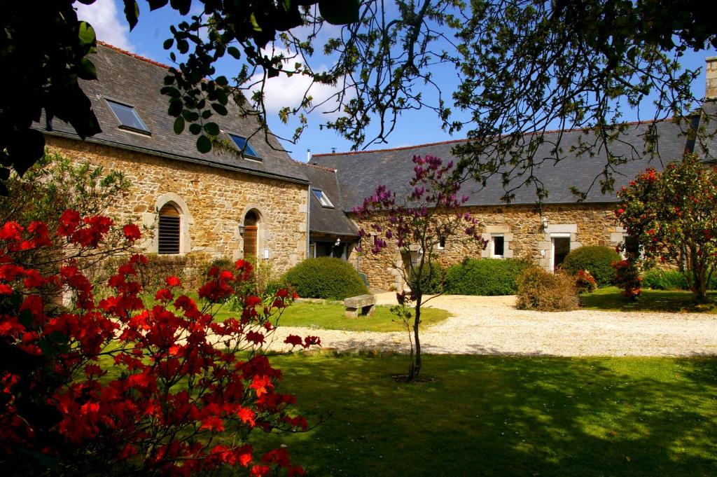 un edificio de piedra con flores rojas delante de él en Le Colombier Bretagne en Louannec