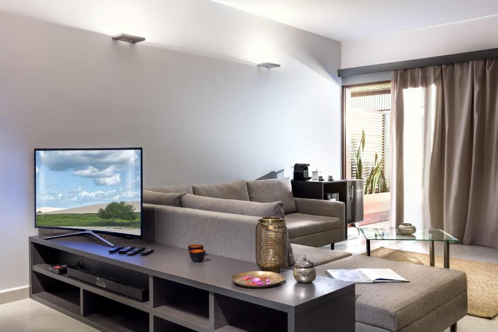 a living room with a couch and a tv at Essenza Dune Hotel in Jericoacoara