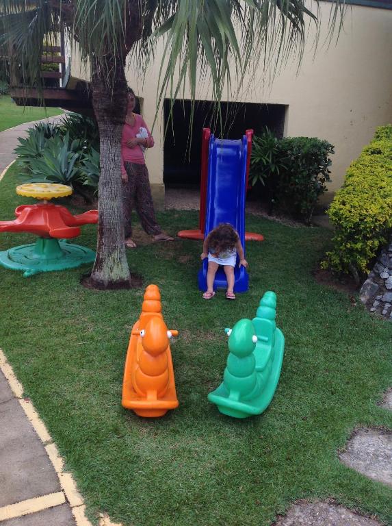 a child playing in a yard with play equipment at Suite Em Buzios JoãƒO Fernandes Praia in Búzios