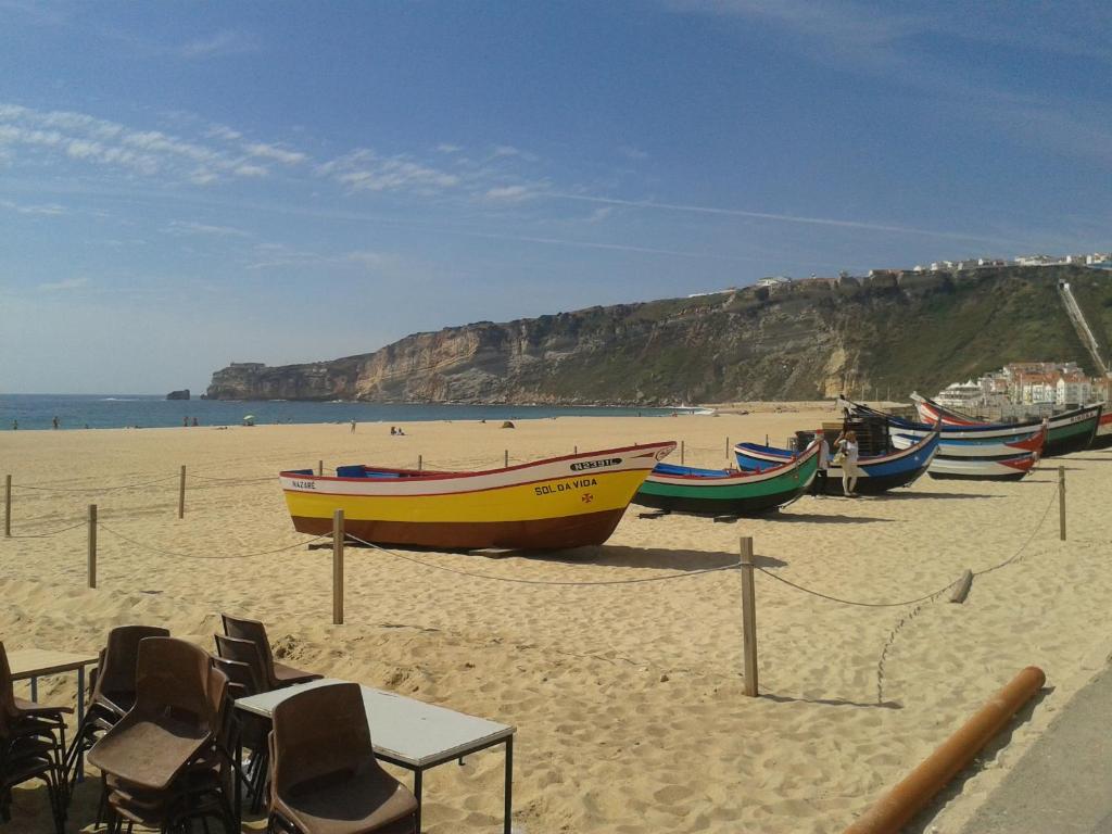 un gruppo di barche sedute su una spiaggia sabbiosa di Apartamento de Férias Nazaré a Nazaré