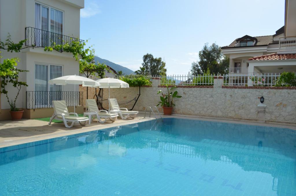 a swimming pool with chairs and umbrellas next to a building at Cam Hotel in Fethiye