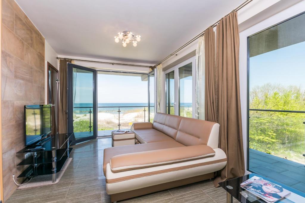 a living room with a couch and a tv at Apartamenty Amon z widokiem na morze in Darlowko