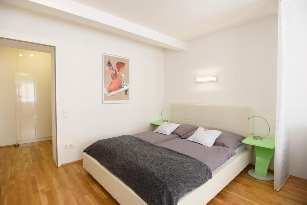ウィーンにあるDesign Apartment - Centrally locatedの白いベッドルーム(ベッド1台、緑のテーブル付)