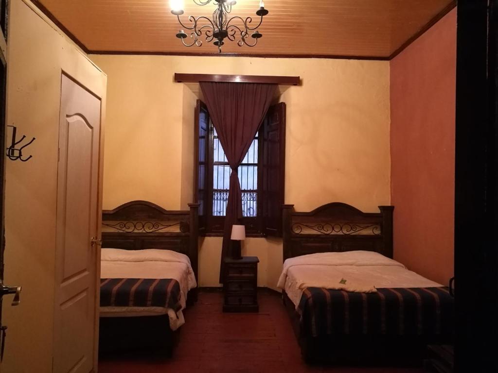 a bedroom with two beds and a window with a chandelier at Hotel Casa Quetzaltenango in Quetzaltenango