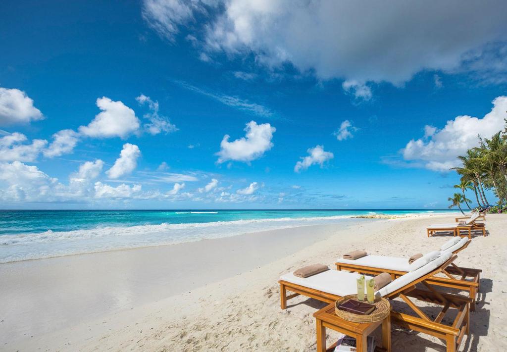 a beach with two lounge chairs and the ocean at Sandals Barbados All Inclusive - Couples Only in Christ Church