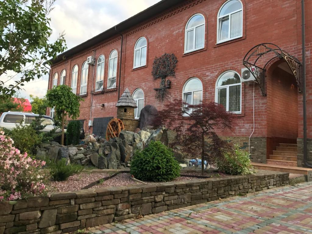 a red brick building with a fountain in front of it at Guesthouse Saksonia in Goryachiy Klyuch