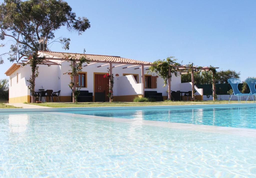 a villa with a swimming pool in front of a house at Casa Das Romãs in Moncarapacho