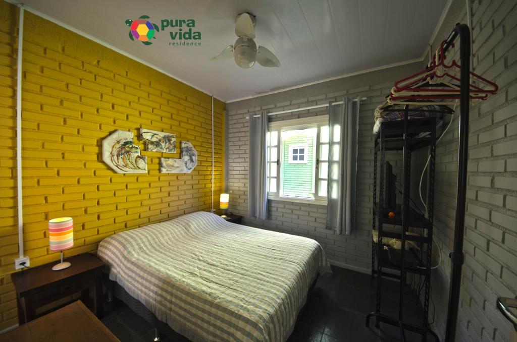 Un dormitorio con una pared de ladrillo amarillo y una cama en Pura Vida Residence en Morretes