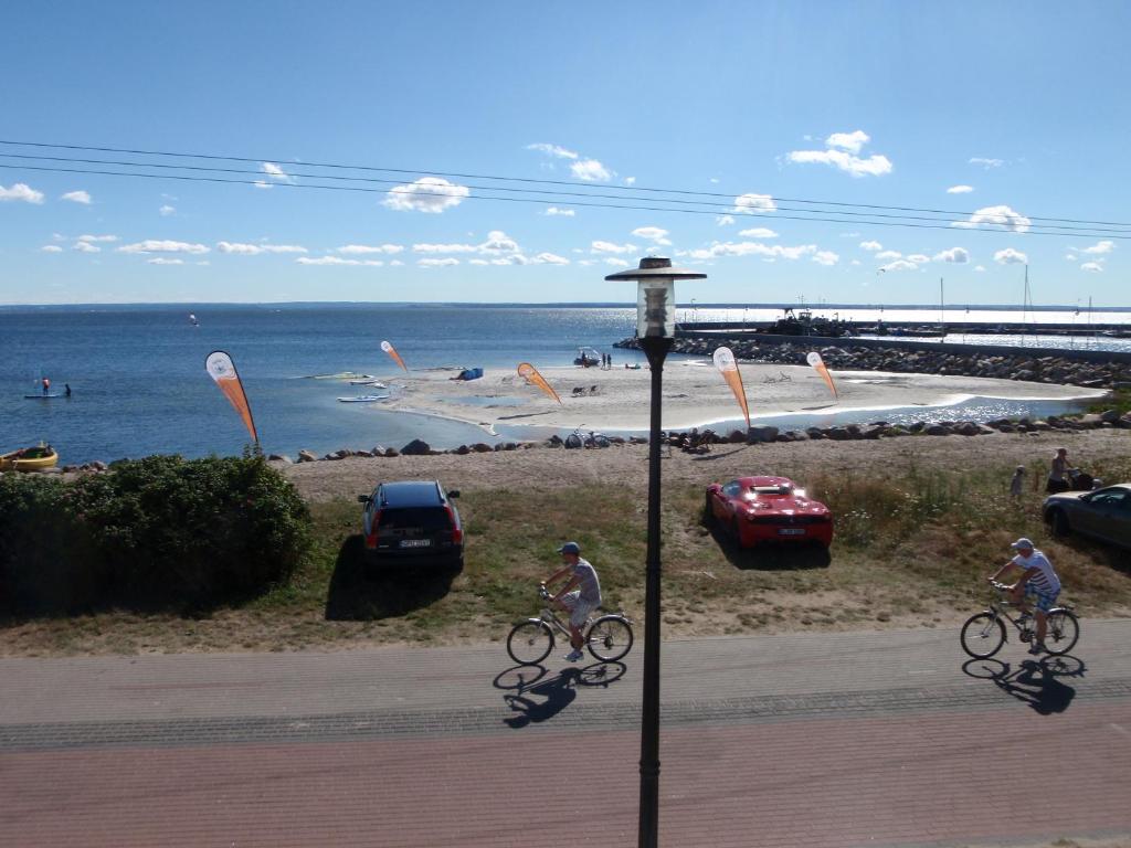 two people riding bikes down a street next to the beach at Kusfeld in Kuźnica