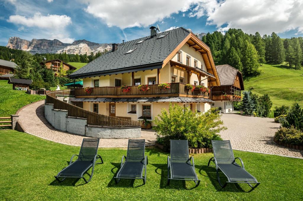 a group of chairs sitting in the grass in front of a house at Taela Apartments in San Cassiano