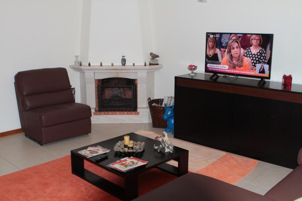 salon z kanapą, telewizorem i krzesłem w obiekcie SolMar e Serra w mieście Alcobaça