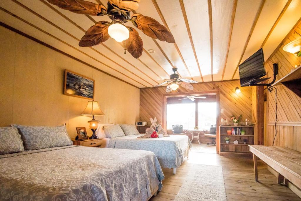 Utila Lodge في أوتاليا: غرفة نوم بسريرين ومروحة سقف