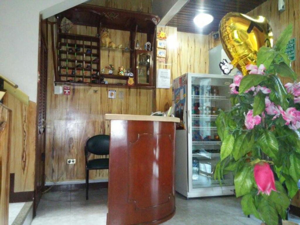 a room with a counter and a refrigerator and flowers at Hotel Boston in Guayaquil