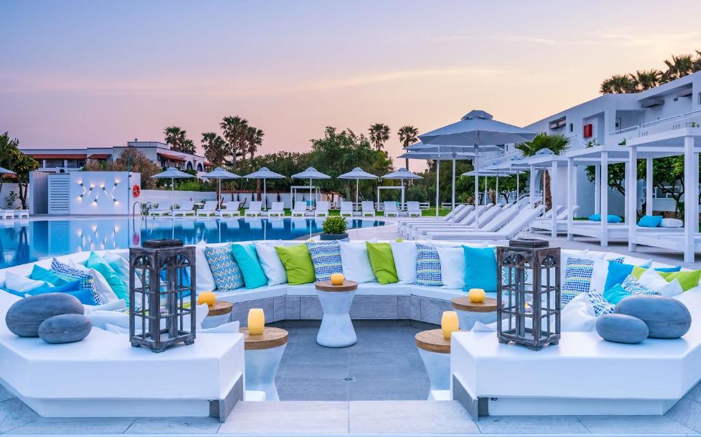 a poolside lounge with couches and chairs next to a pool at Gaia in Style - Adults Only in Tigaki