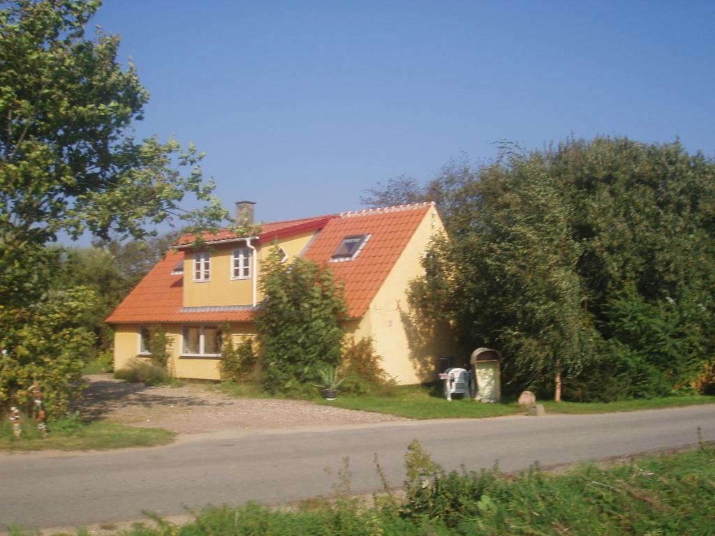 een geel huis met een oranje dak op een weg bij Country house in Karby